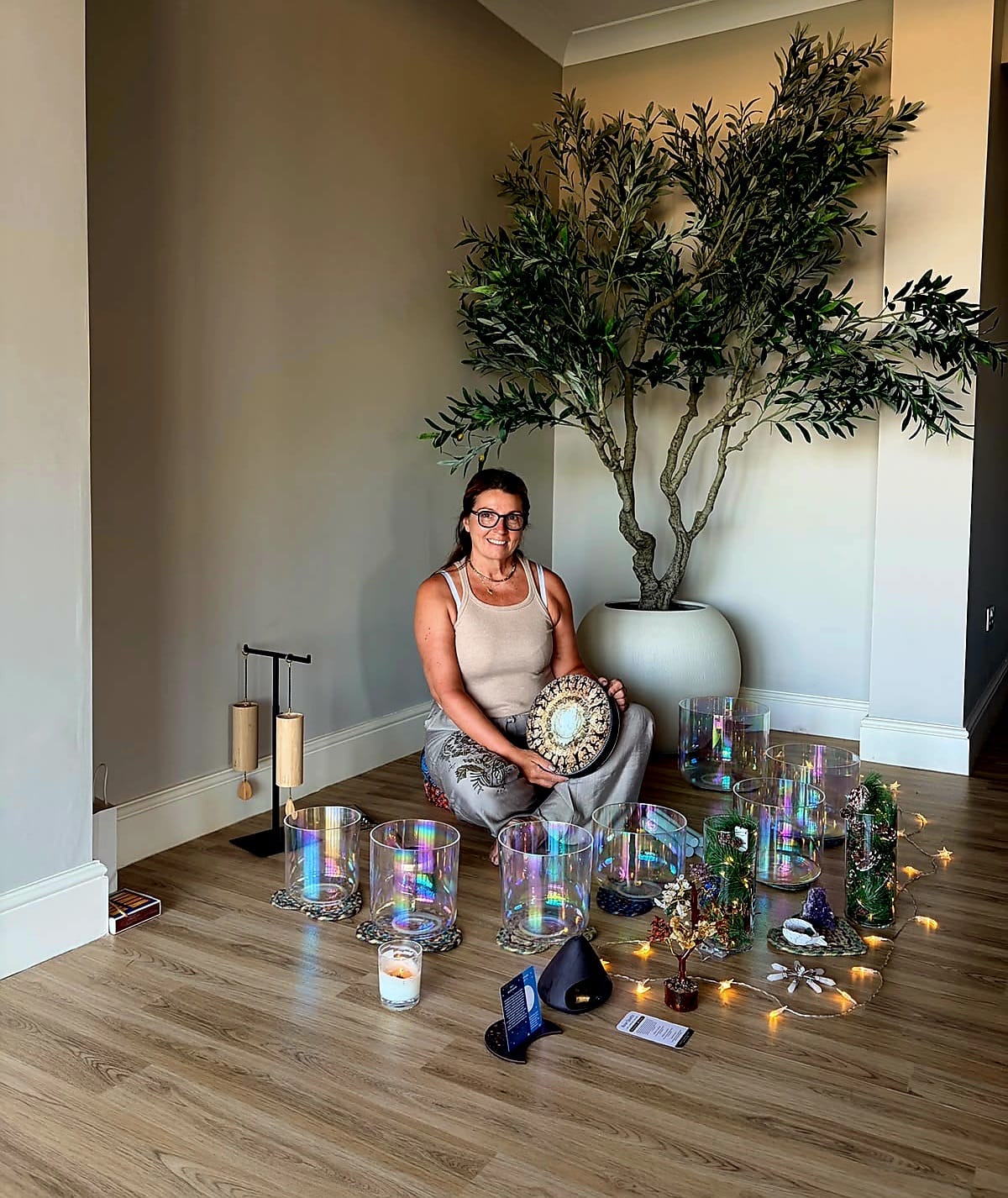 Karen smiling, seated among a circle of crystal singing bowls